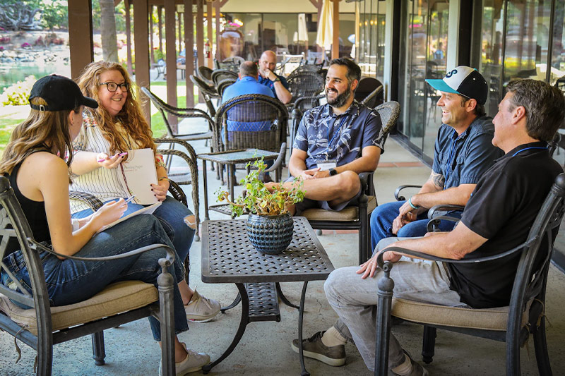 A small group sits and talks around a patio table