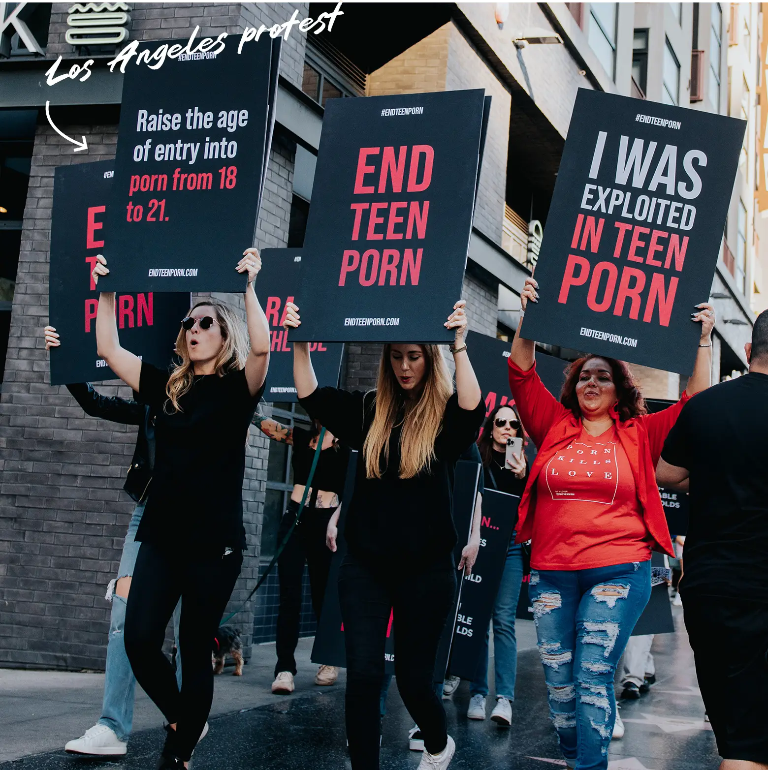 A group of women protest on the streets of LA, holding up signs like 'Raise the age of entry from 18 to 21' and 'END TEEN PORN'