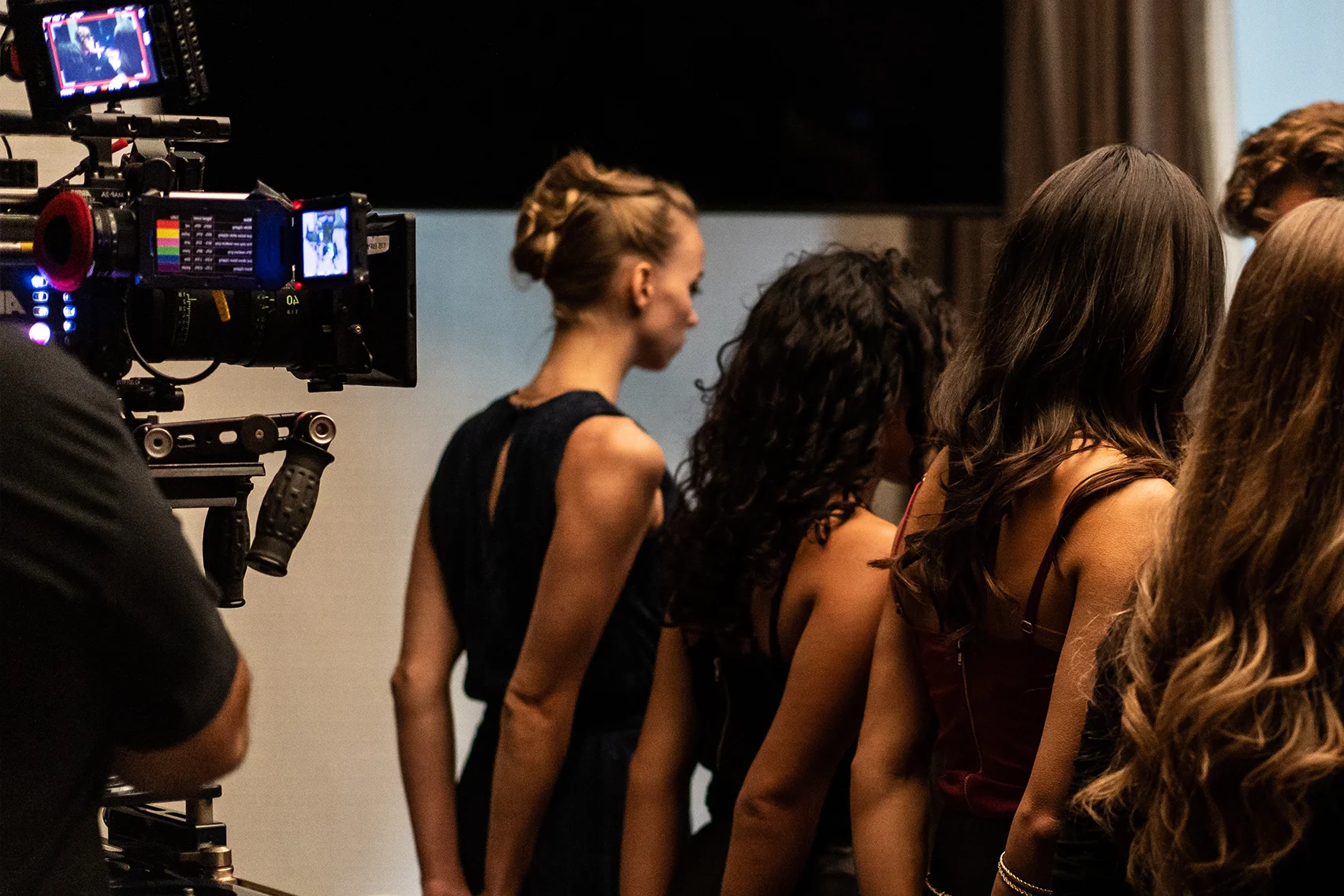 A film set shows a camera filming a group of girls